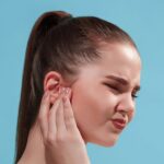 sore-ear-sad-crying-woman-with-headache-pain-trendy-blue-studio-background