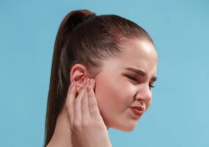 sore-ear-sad-crying-woman-with-headache-pain-trendy-blue-studio-background